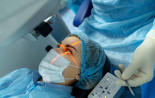 A person in surgical scrubs and mask undergoing eye surgery.