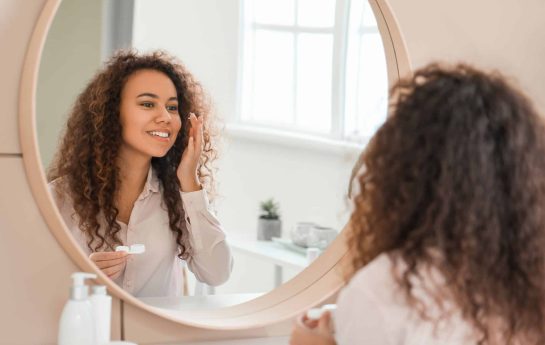 Woman putting her contacts in whilst looking in the mirror