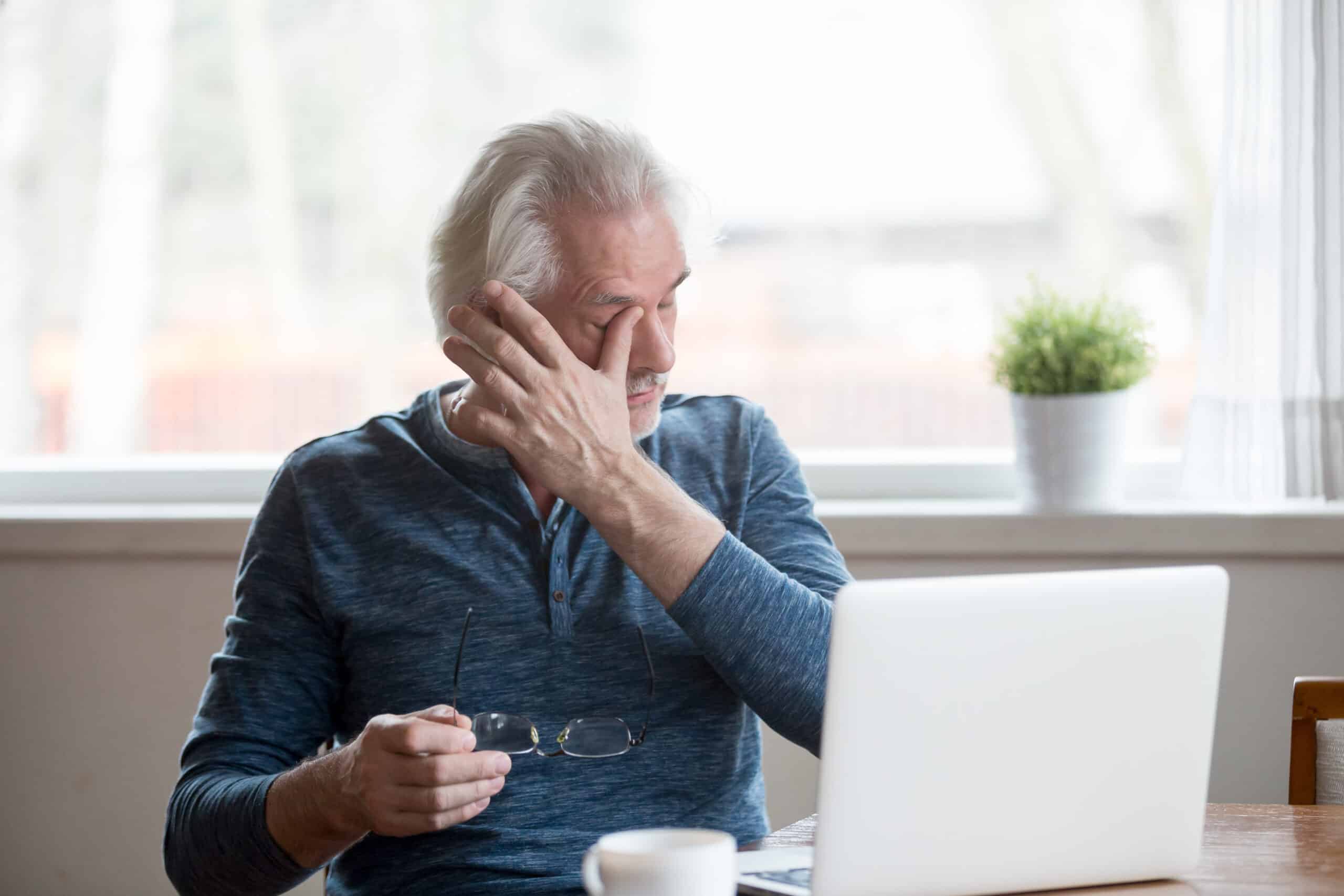 man taking his glasses off and wiping his eye