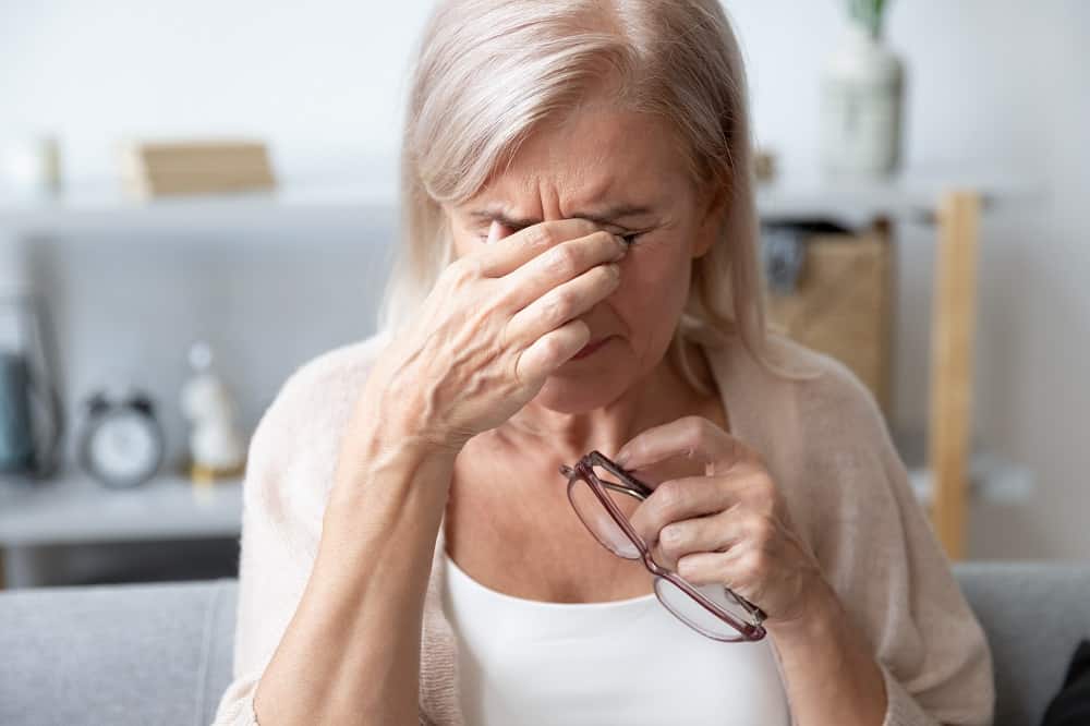 elderly woman crying and holding her eyes