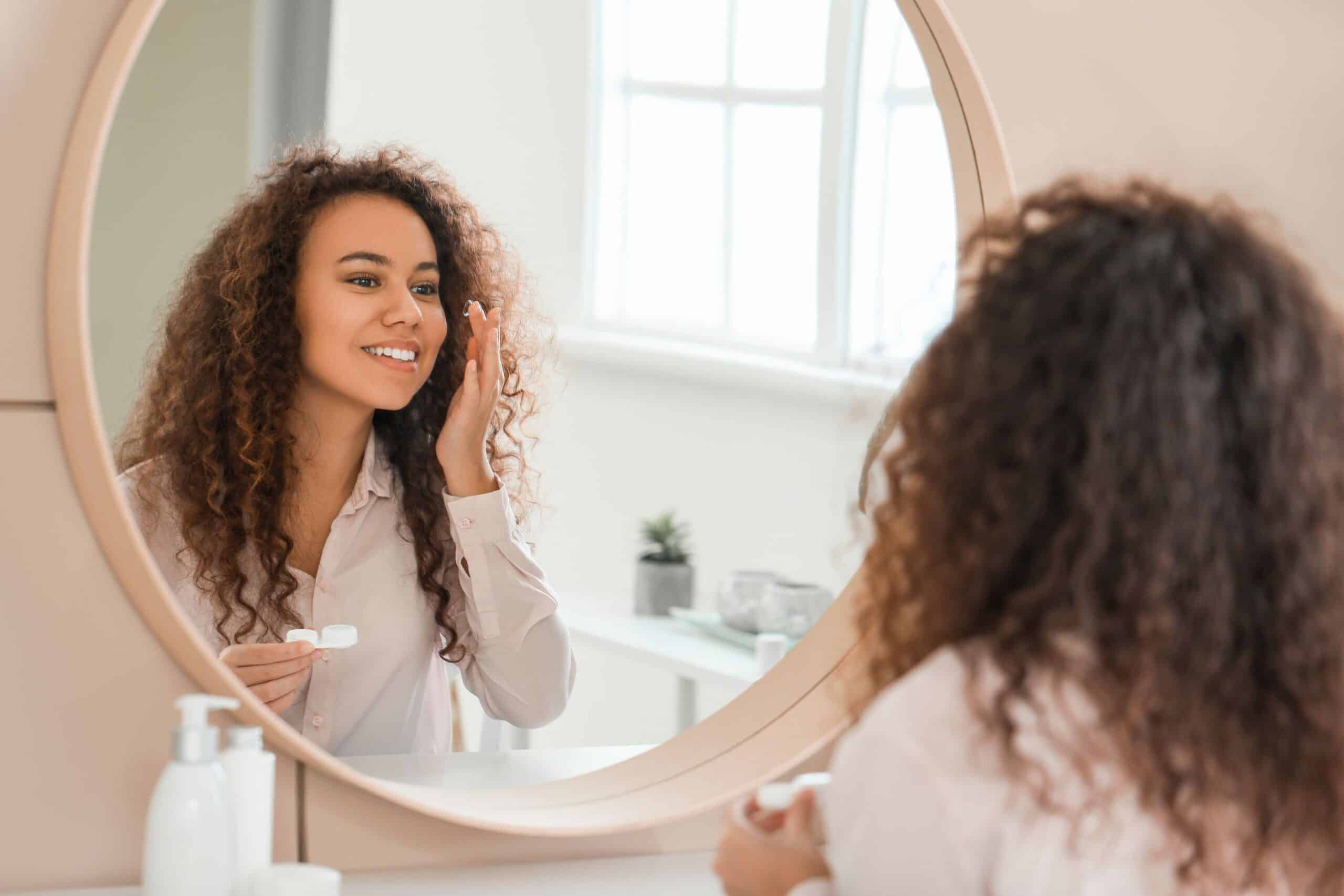 Woman putting her contacts in whilst looking in the mirror