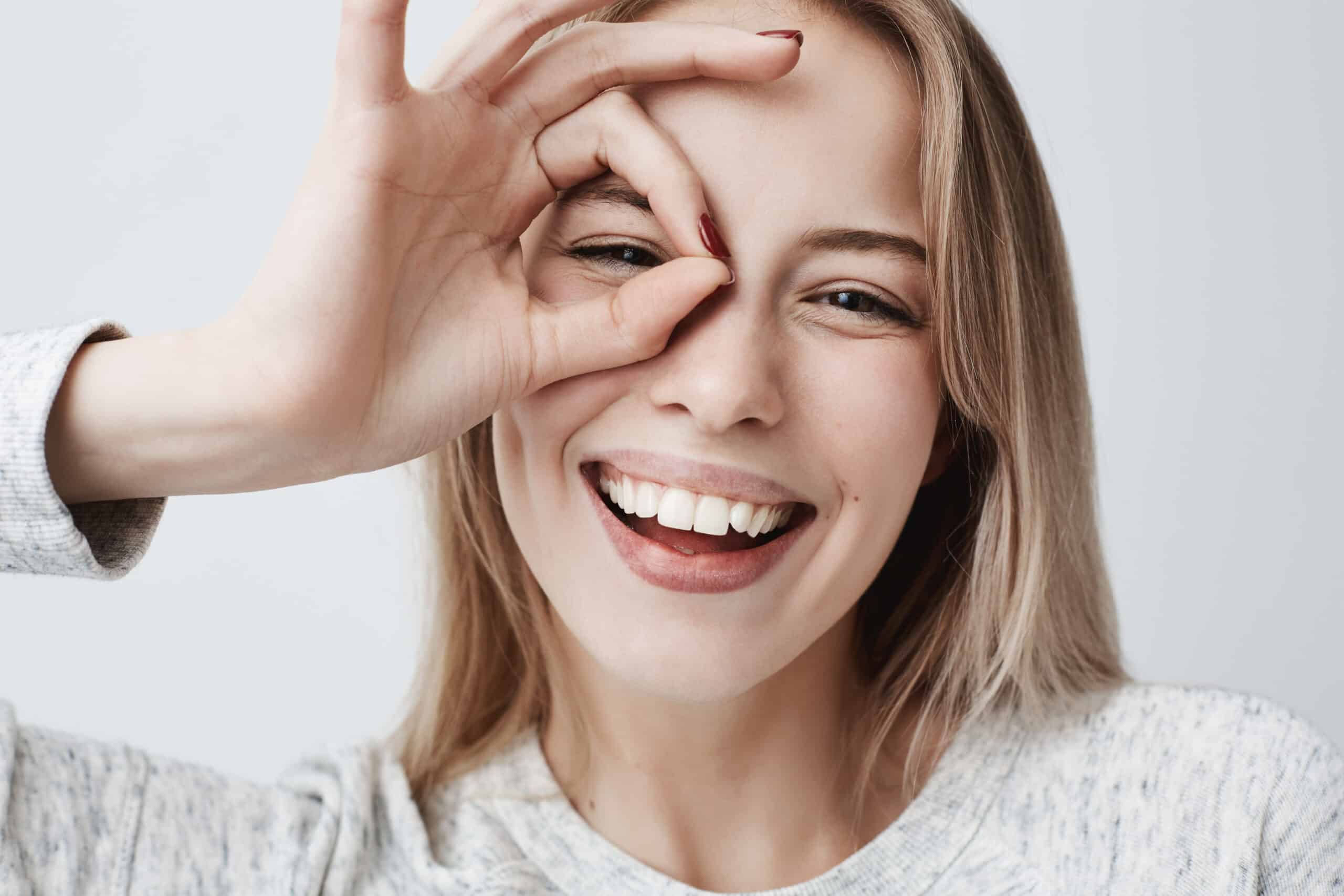 Close-up of a smiling female making the OK sign with her hands around her eye.